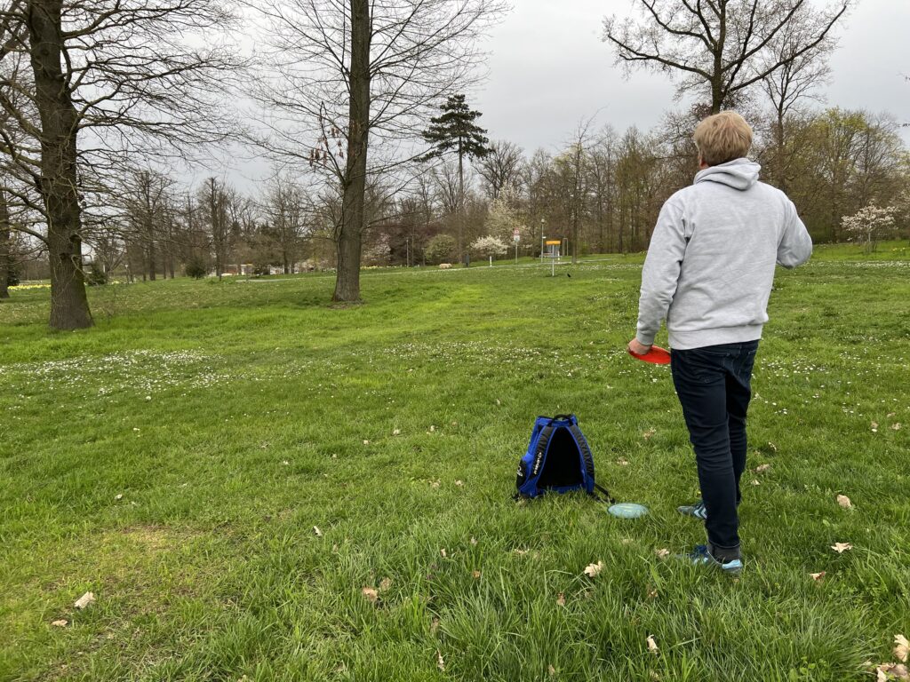 Ein Mann der auf dem Disc Golf Platz in Bad Nauheim steht und eine Disc Golf Scheibe in der Hand hat.