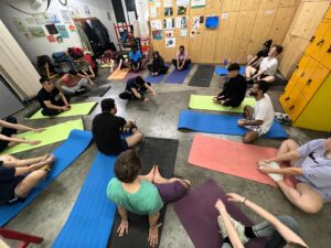 Menschen in Sportkleidung, die auf bunten Yogamatten im Kreis sitzen